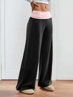 Person wearing black wide-leg pants with a pink waistband on a white background