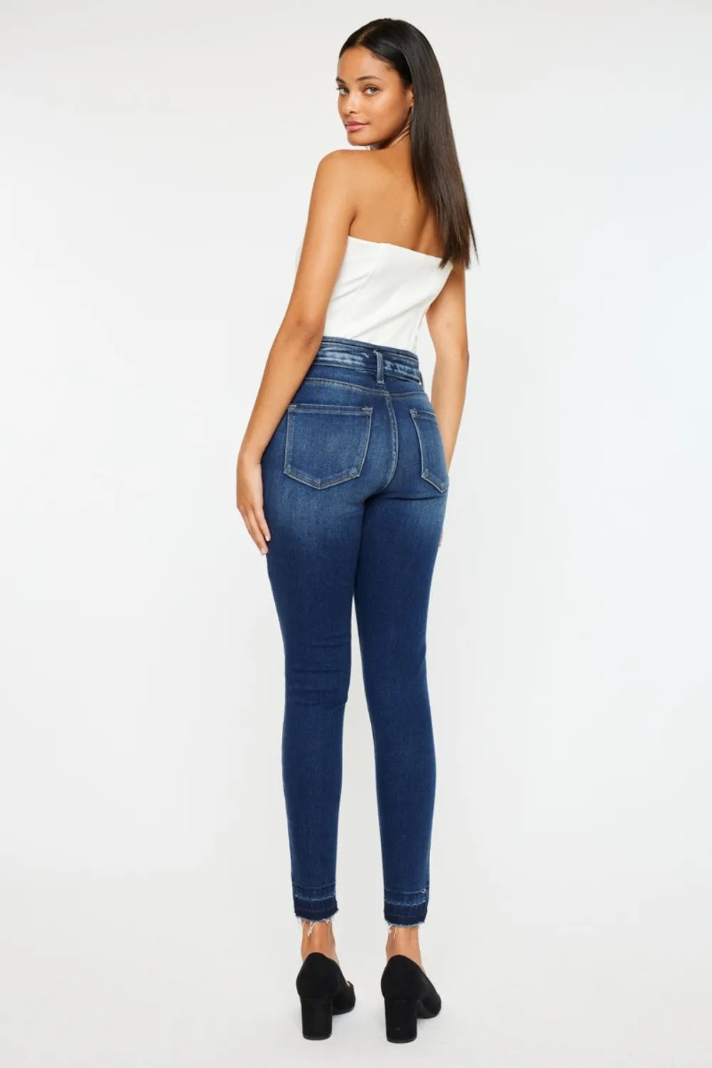 Woman wearing blue jeans and a white top on a white background