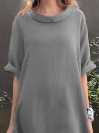 Person wearing a gray dress with a plain background
