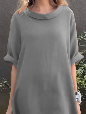Person wearing a gray dress with a plain background