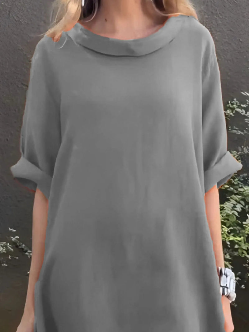 Person wearing a gray dress with a plain background