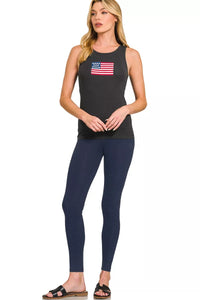 Woman wearing a black tank top with an American flag design and navy leggings on a white background