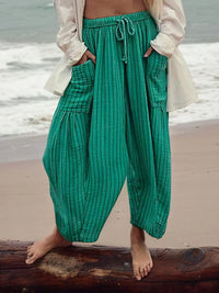 Person wearing green pants standing on a beach with ocean in the background