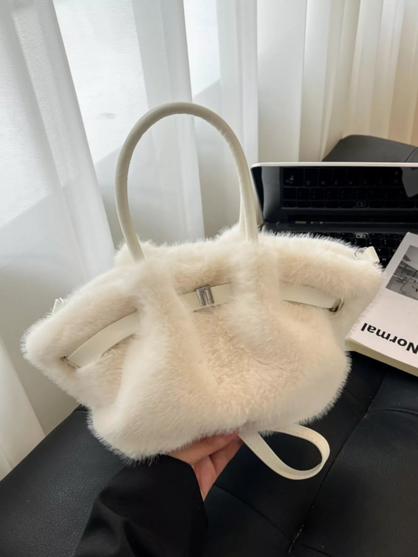 White fluffy handbag held in front of a blurred indoor background