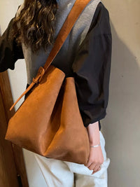 Person wearing a brown leather shoulder bag against a neutral background
