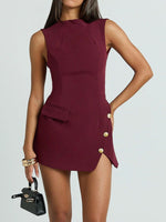 Woman wearing a burgundy dress with gold buttons on a plain background