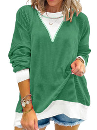 Green sweater with white trim worn by a person on a white background