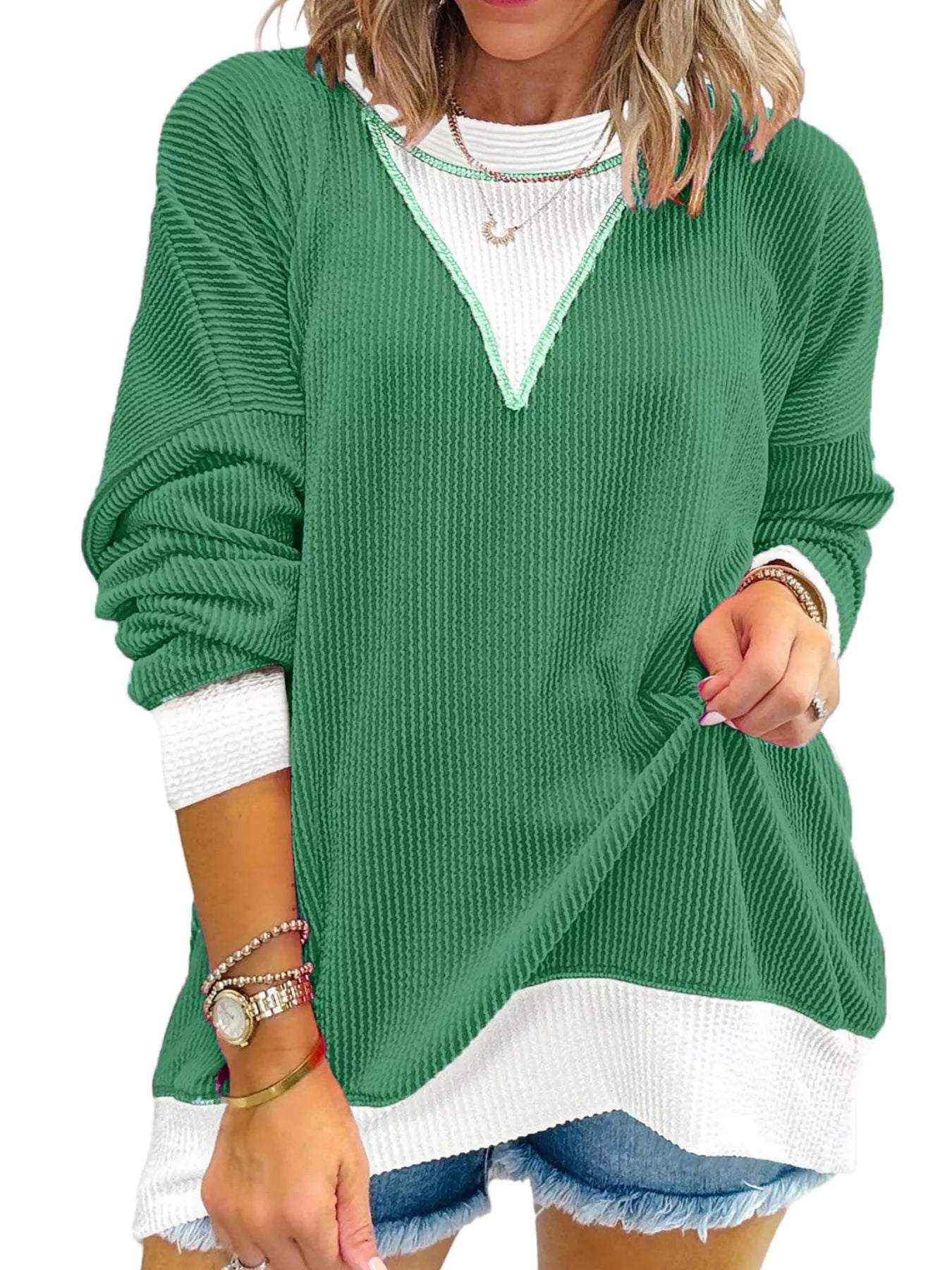 Green sweater with white trim worn by a person on a white background
