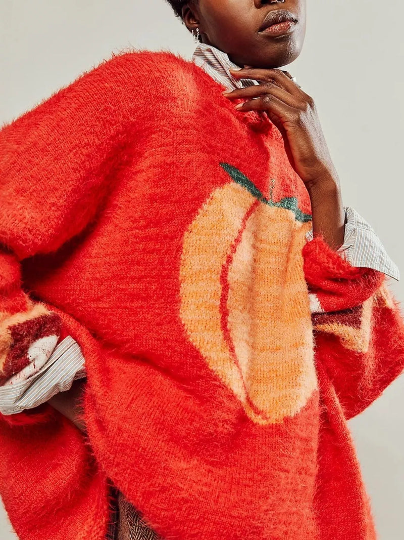 Person wearing a red sweater with a pumpkin design on a plain background