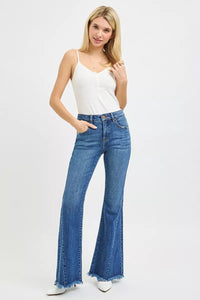 Woman wearing blue flared jeans and a white tank top on a white background