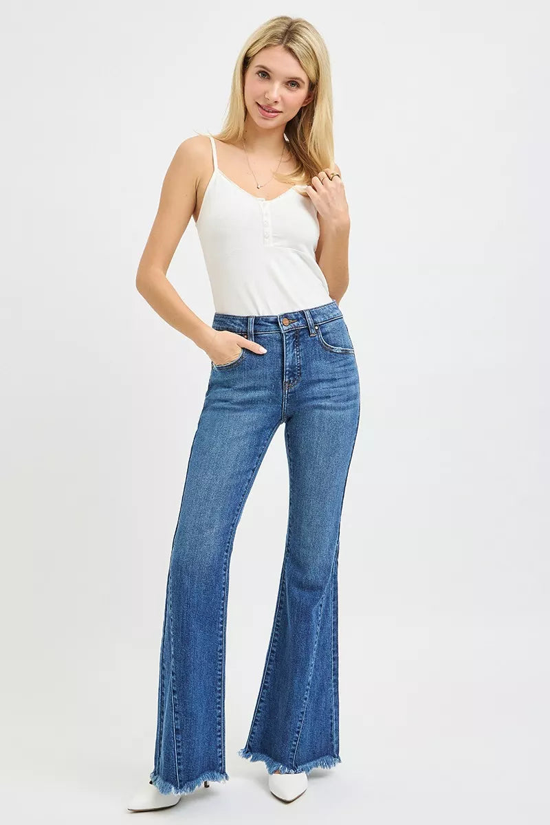 Woman wearing blue flared jeans and a white tank top on a white background