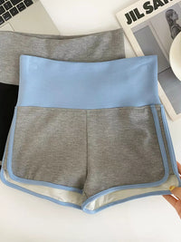 Gray shorts with blue trim held in front of a laptop and magazine.