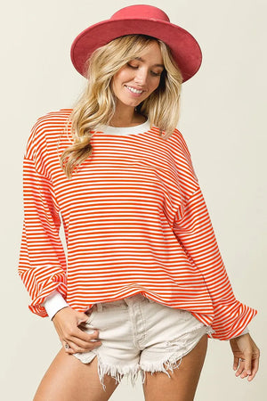 Woman wearing a red and white striped long-sleeve top and a red hat on a beige background