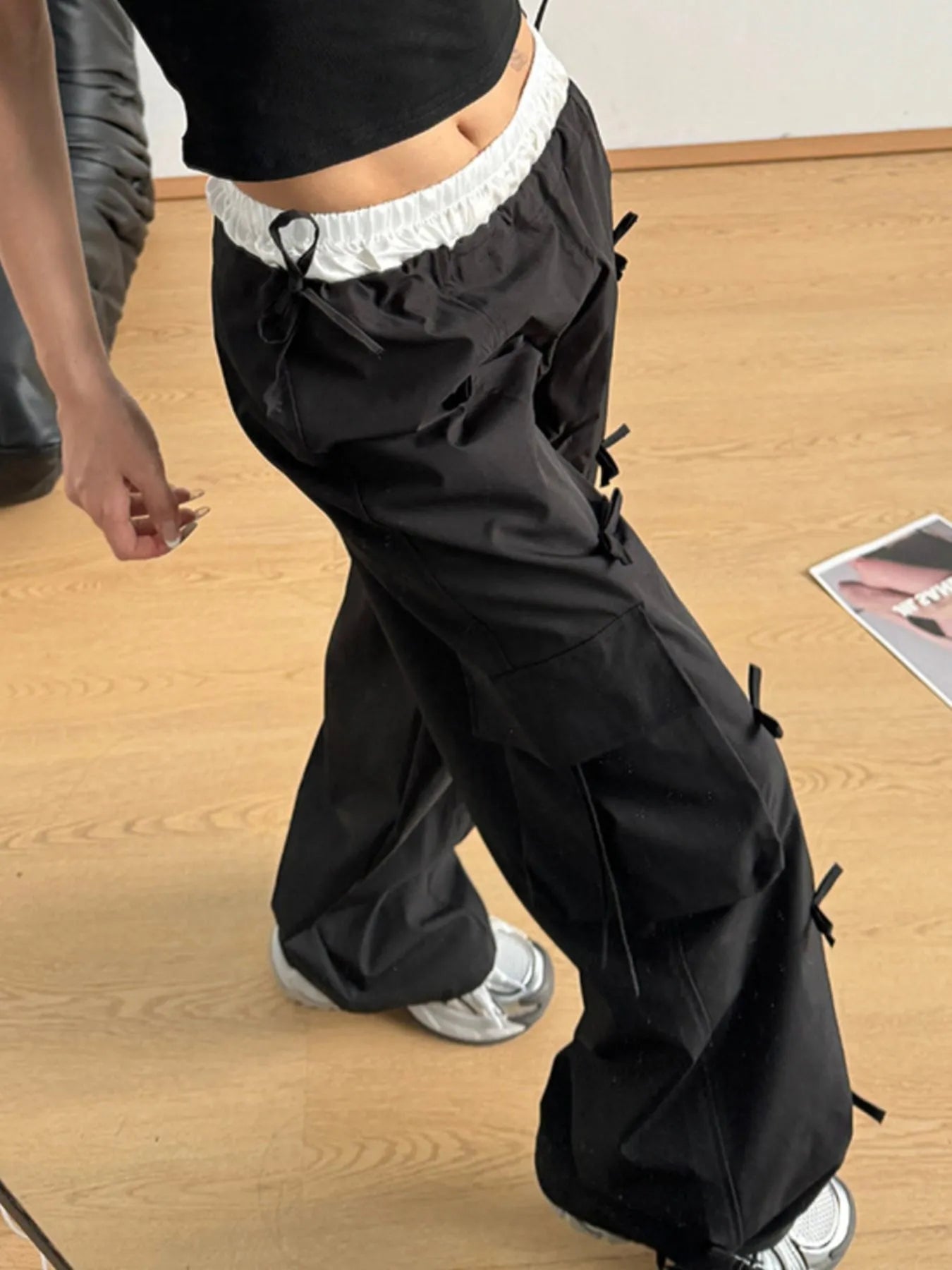 Person wearing black cargo pants on a wooden floor