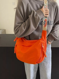 Person holding an orange bag with a colorful strap indoors