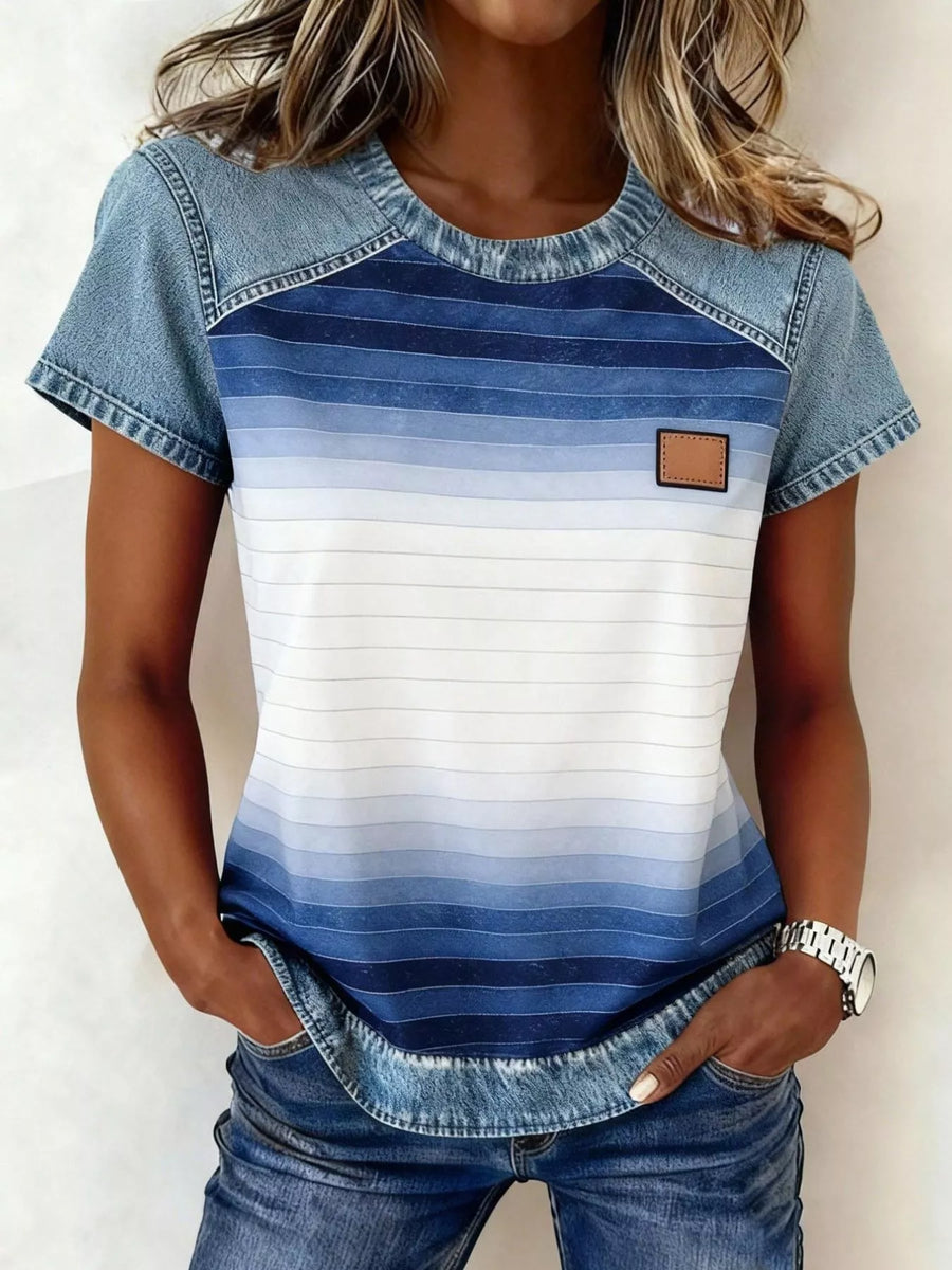 Woman wearing a blue and white striped shirt with denim accents on a plain background