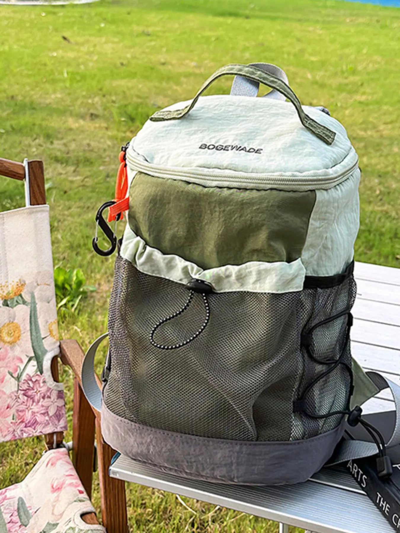 Green and gray backpack with a visible brand logo on a chair outdoors.