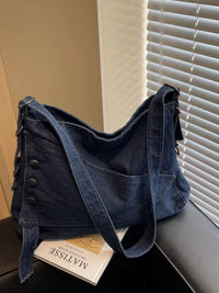 Blue denim bag on a surface with a book underneath, against a neutral background.