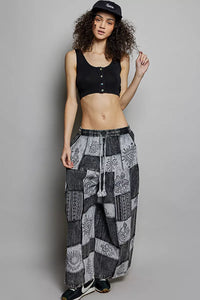 Woman wearing a black crop top and patterned pants against a gray background