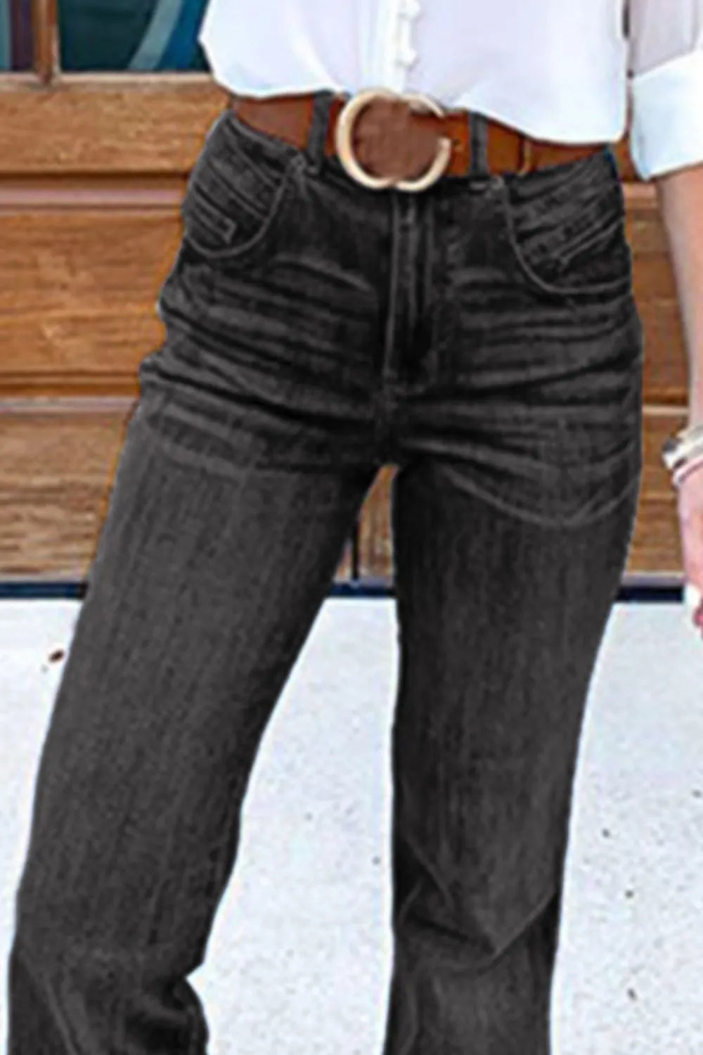 Person wearing dark jeans with a belt in an outdoor setting