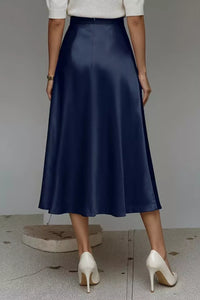 Person wearing a navy blue skirt and white shoes on a neutral background