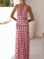Woman wearing a pink dress with black polka dots in an outdoor setting.