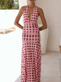 Woman wearing a pink dress with black polka dots in an outdoor setting.