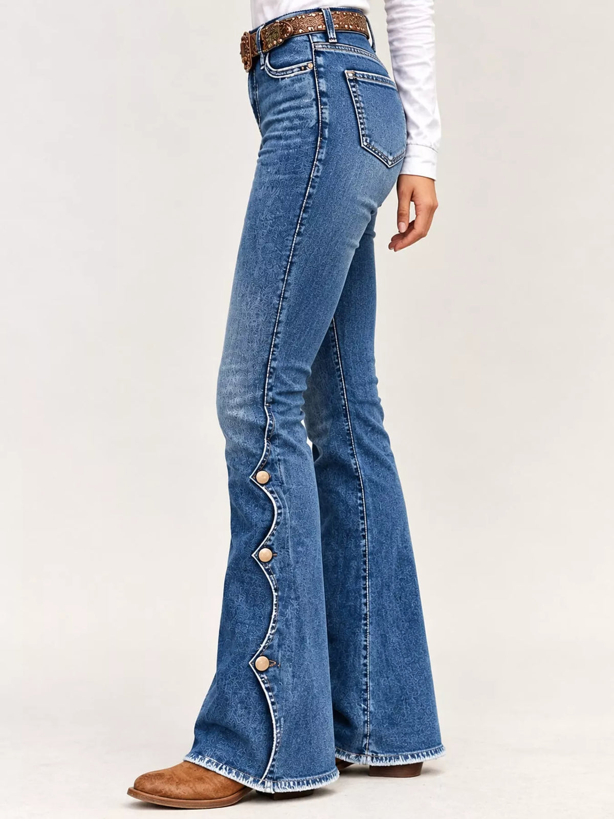 A person wearing blue high-rise flare jeans with decorative buttons down the outer leg, styled with a brown belt and brown boots against a light gray studio background.