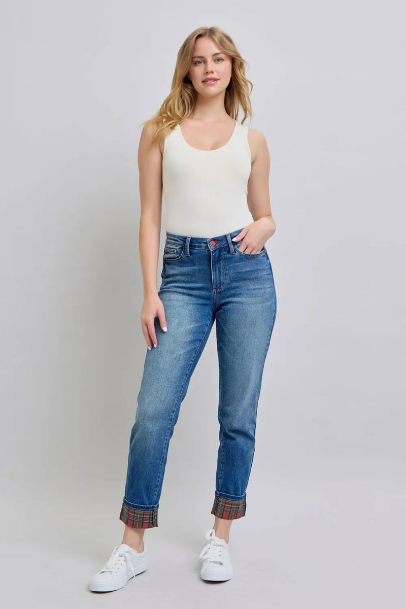 Woman wearing a white tank top and blue jeans on a plain background