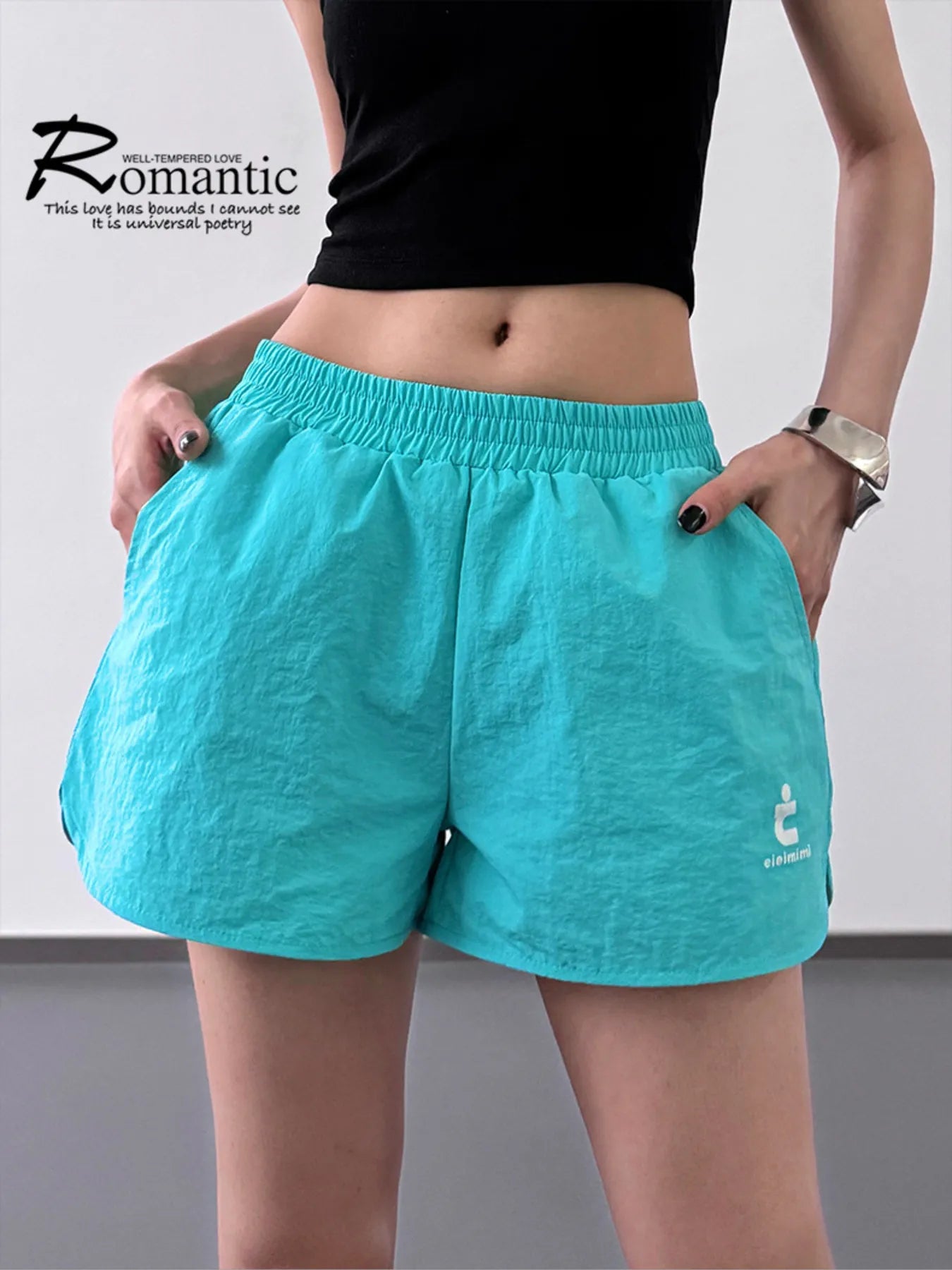 Person wearing turquoise shorts with a logo on a plain background
