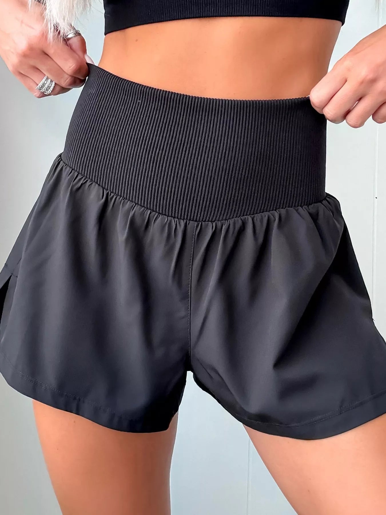 Black athletic shorts being worn against a neutral background