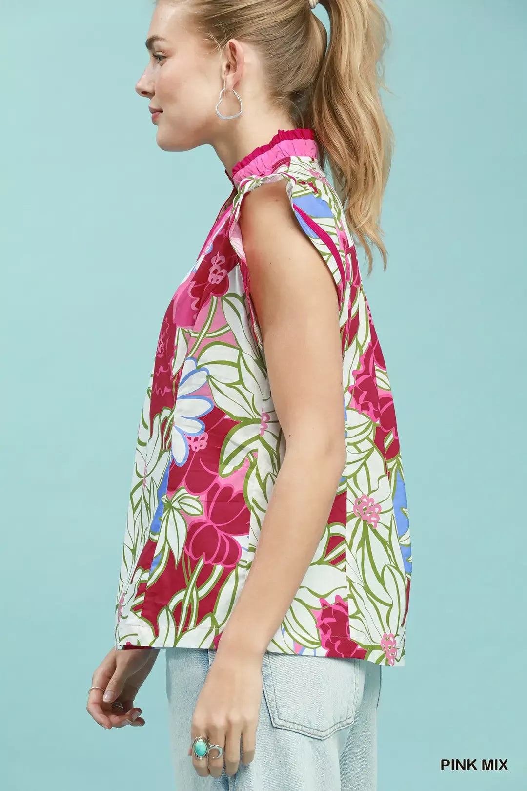 Woman wearing a colorful floral sleeveless top against a light blue background