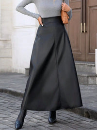 Person wearing a long black skirt with a gray top and black shoes on a street.