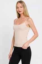 Woman wearing a beige tank top and black pants on a white background