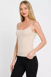 Woman wearing a beige tank top and black pants on a white background