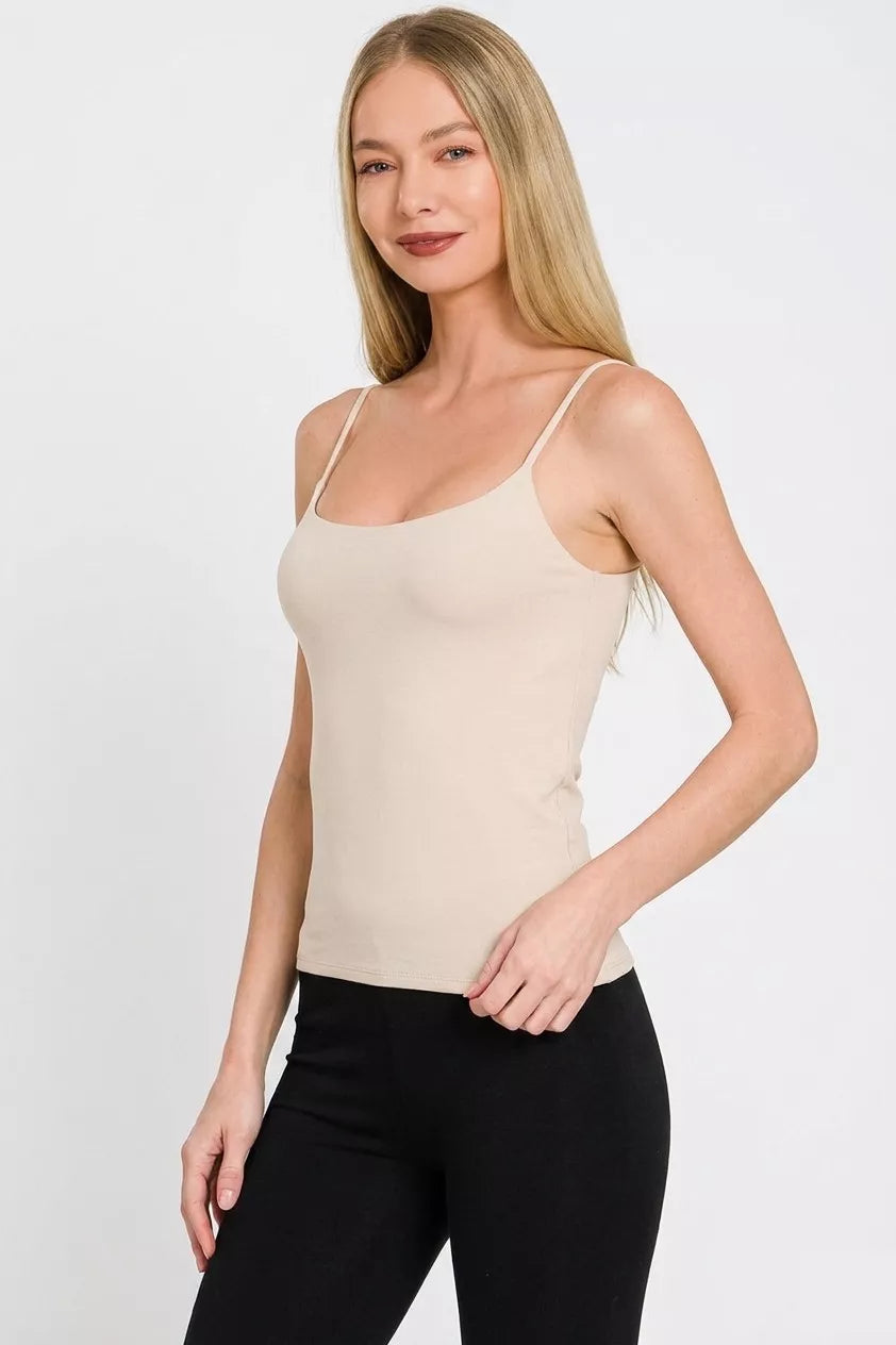 Woman wearing a beige tank top and black pants on a white background