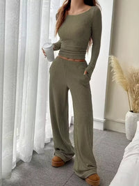 Person wearing a green ribbed knit outfit holding a coffee cup indoors.