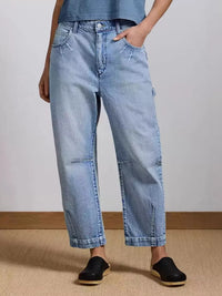 Person wearing light blue jeans and black shoes on a plain background