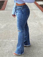 Person wearing blue flared jeans on a sidewalk