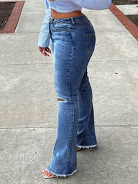 Person wearing blue flared jeans on a sidewalk