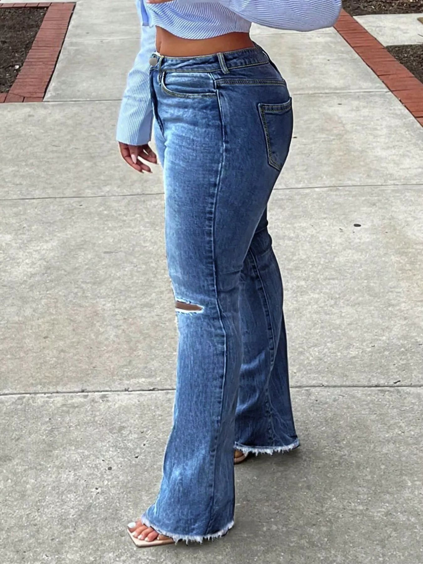 Person wearing blue flared jeans on a sidewalk