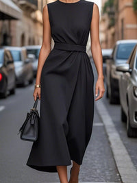 Woman wearing a black sleeveless dress on a city street.