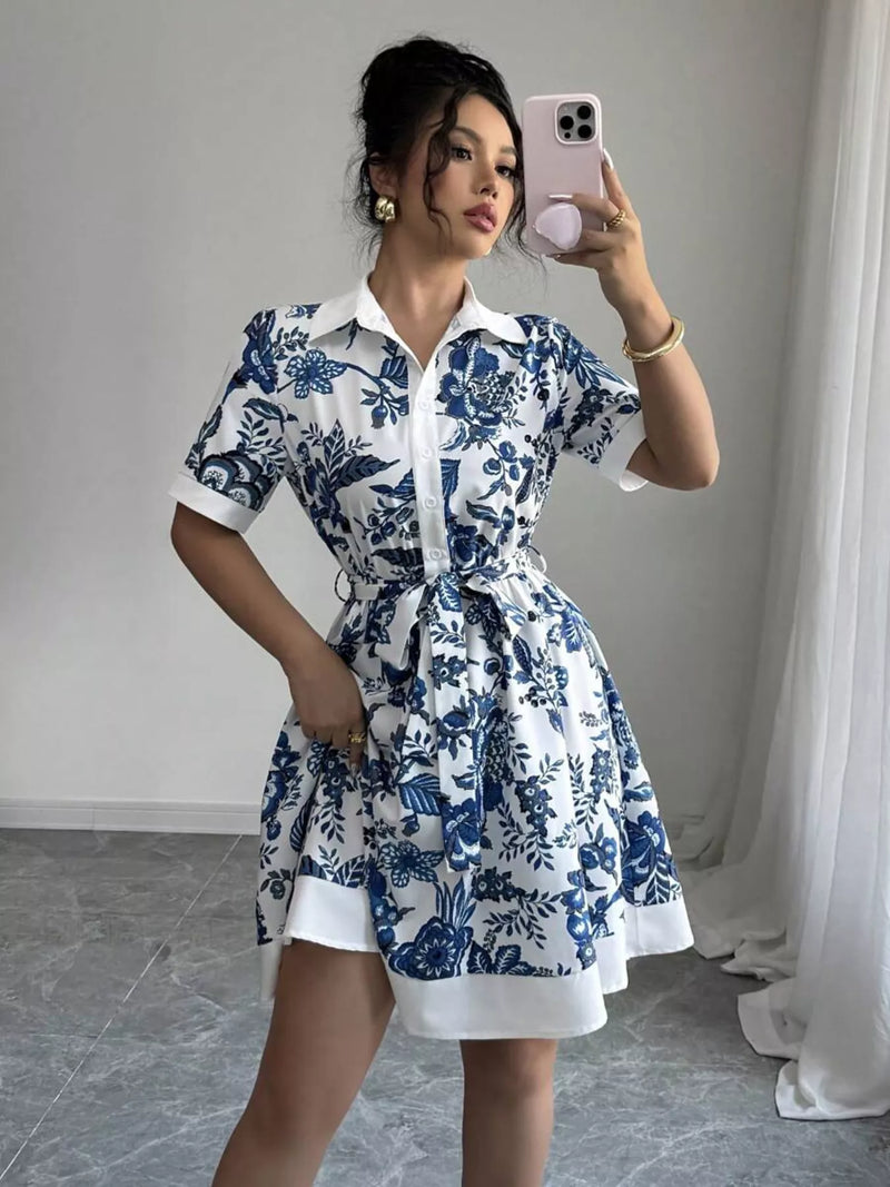 Woman taking a mirror selfie wearing a blue and white floral dress.