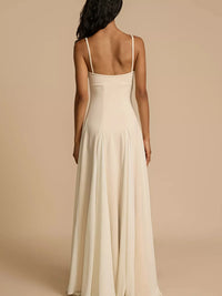 Woman wearing a long, light-colored dress with thin straps on a beige background