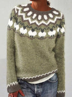 Person wearing a green knitted sweater with a white pattern on a plain background