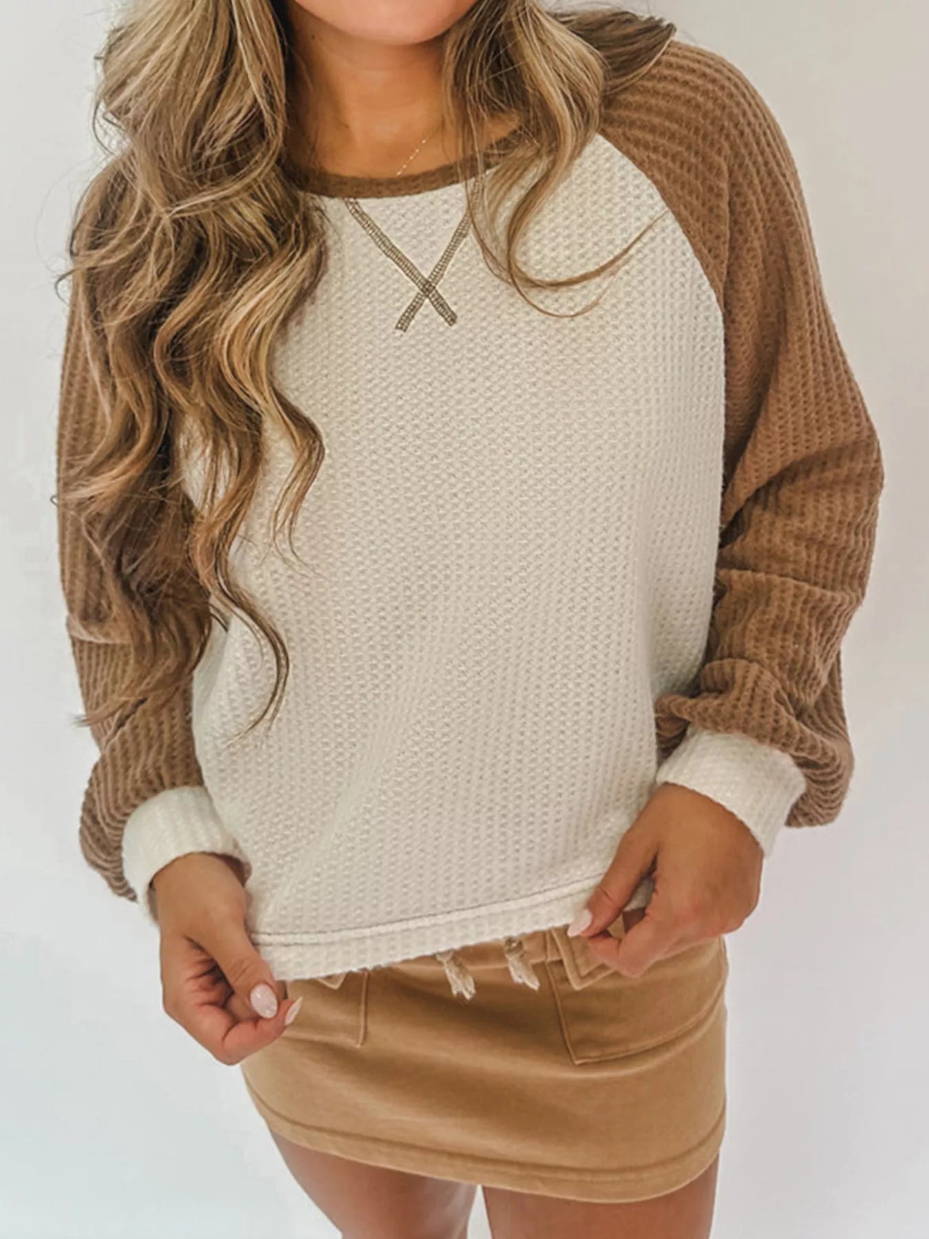 Person wearing a beige and brown sweater with a plain background