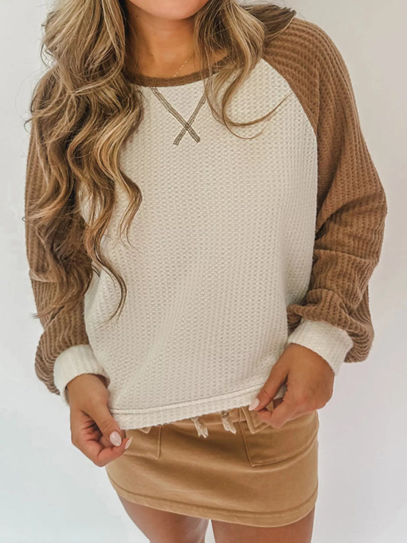 Person wearing a beige and brown sweater with a plain background
