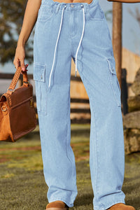 Person wearing light blue cargo pants holding a brown leather bag outdoors.