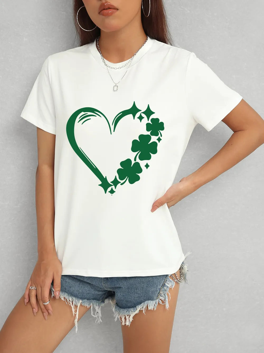 Person wearing a white t-shirt with a green shamrock design on a gray background