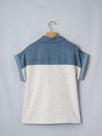 Two-tone blue and gray shirt on a hanger against a light gray background